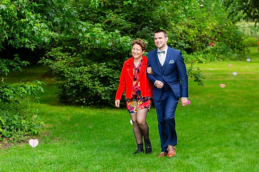 Groom walking down the aisle with his mother