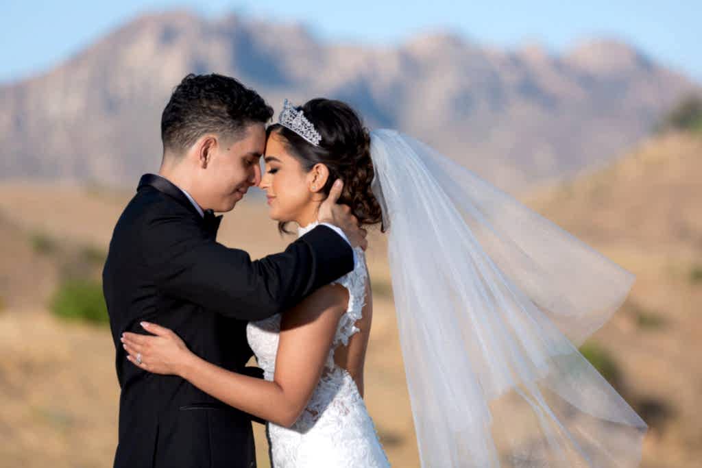 bride and groom embracing with a mountain range in the distance for their outdoor wedding in Malibu, California
