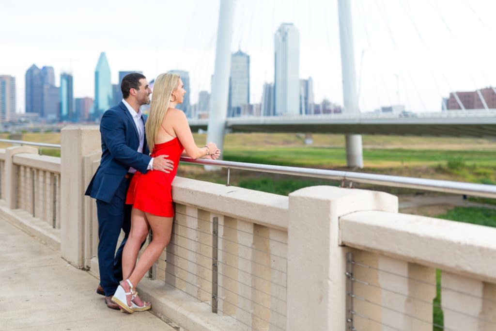 woman in red dress and man in blue suit admiring dallas skyline