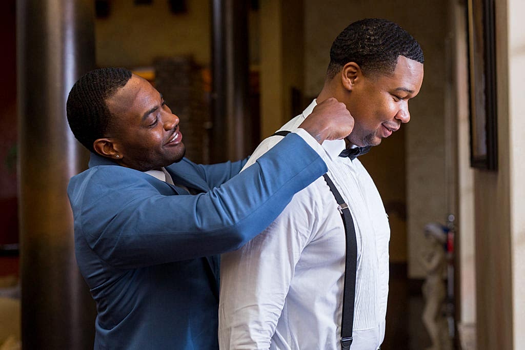 Best man helping groom putting on bow tie