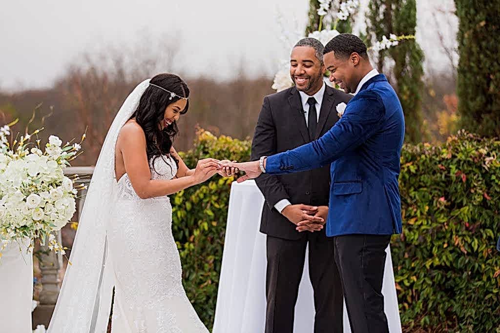 Bride putting ring on grooms hand at their outdoor wedding ceremony during their Dallas weddings