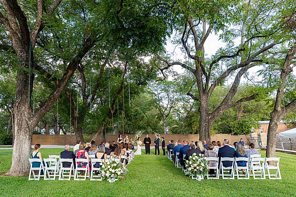 Grassy ceremony site with tall trees at Hotel Lucy in Granbury
