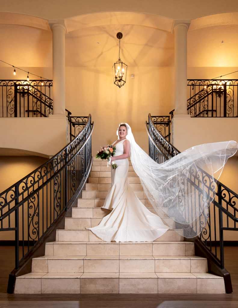 stunning portrait of bride on grand staircase with a veil in a luxury wedding venue chapel at ana villa