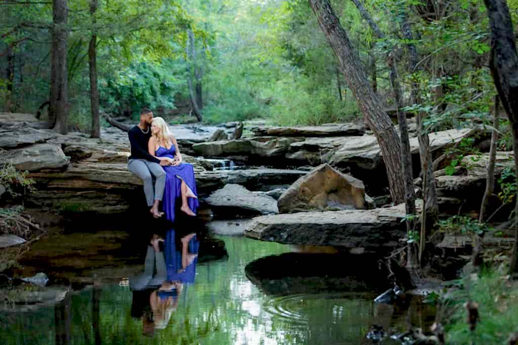 Engaged couple sitting on rocks at stone creek park in flower mound
