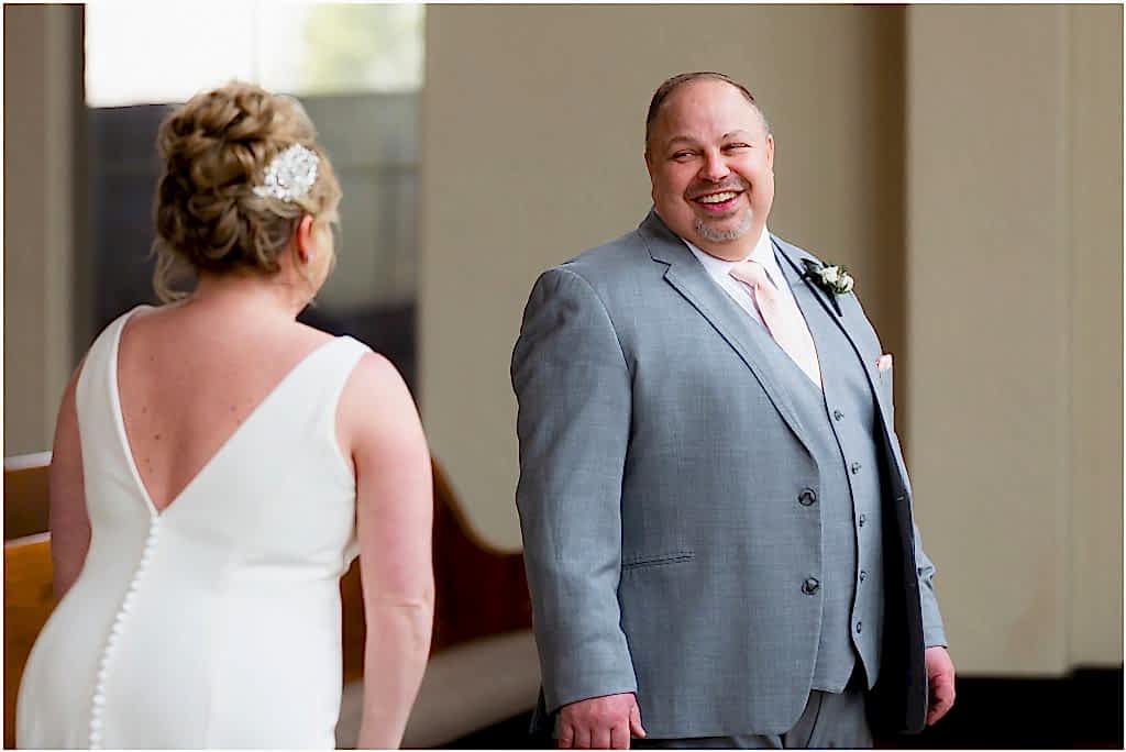 Groom Chris looks at bride lovingly during their first look in Ana Villa wedding venue chapel captured by Dallas wedding photographer