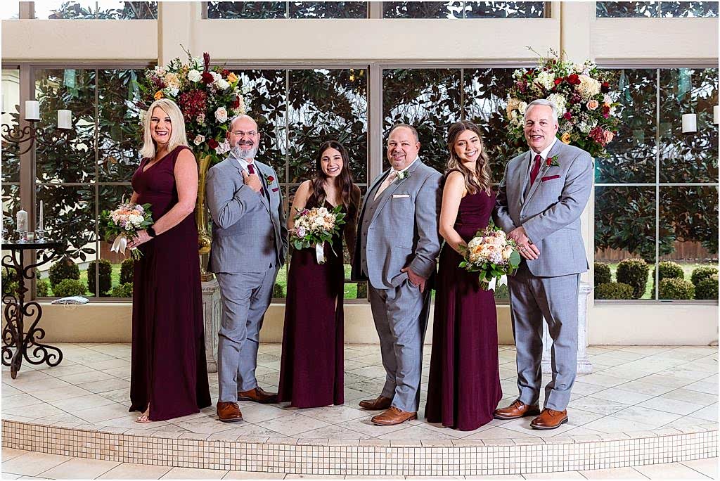 Groom's family pose together in front of floral arrangements for Dallas wedding photographers