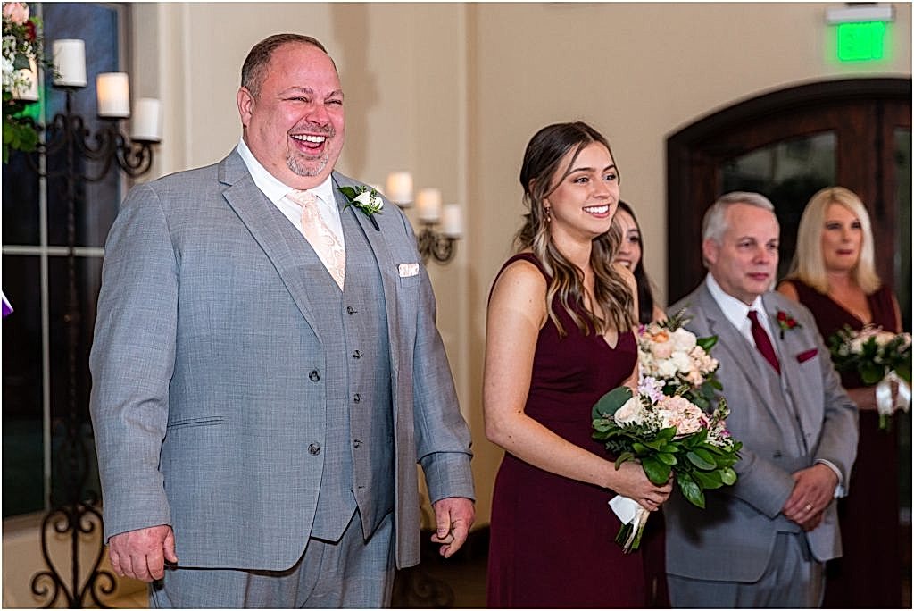 Groom and bridal party laugh and cry as they see the bride come down the aisle captured by Dallas wedding photographers