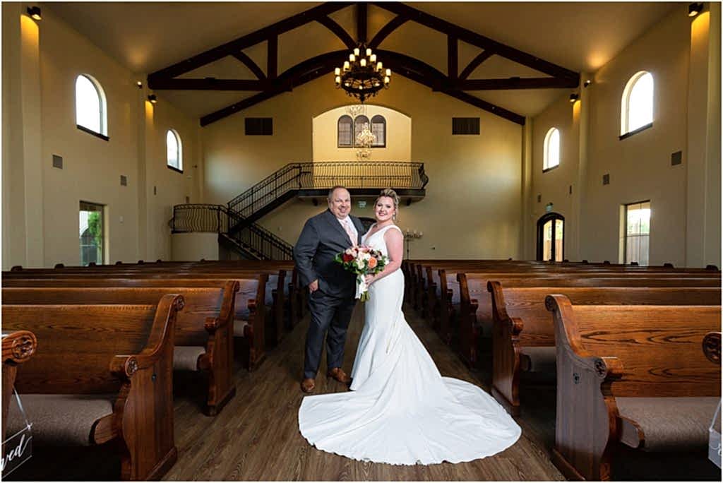 bride and groom in chapel at ana villa amidst pews photographed by Dallas wedding photographer
