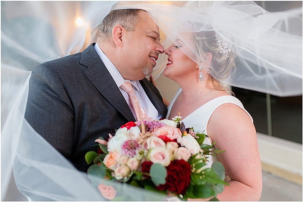 intimate and unique veil shot of bride and groom leaning into each other to kiss photographed by Dallas wedding photographers
