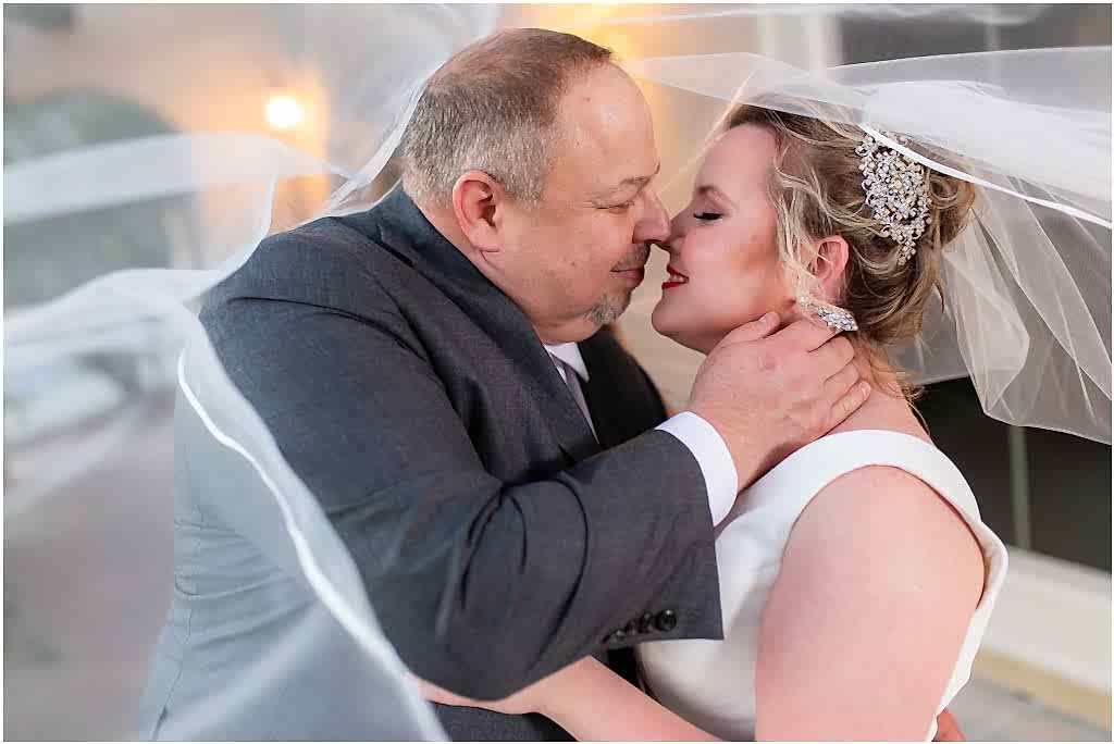 Dallas wedding photographers capture the bride and groom almost kissing under a veil in a Dallas wedding venue