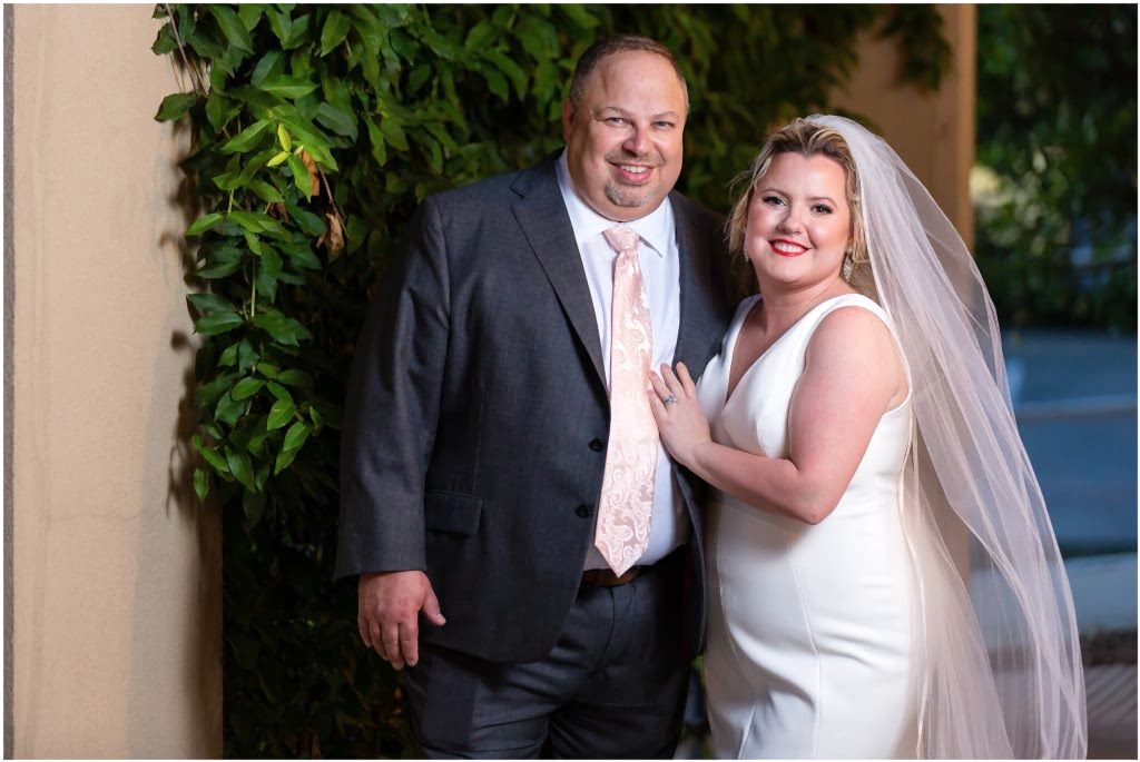 A bride and a groom in a grey suit with a paisley tie stand together at a Dallas wedding venue captured by Dallas wedding photographers
