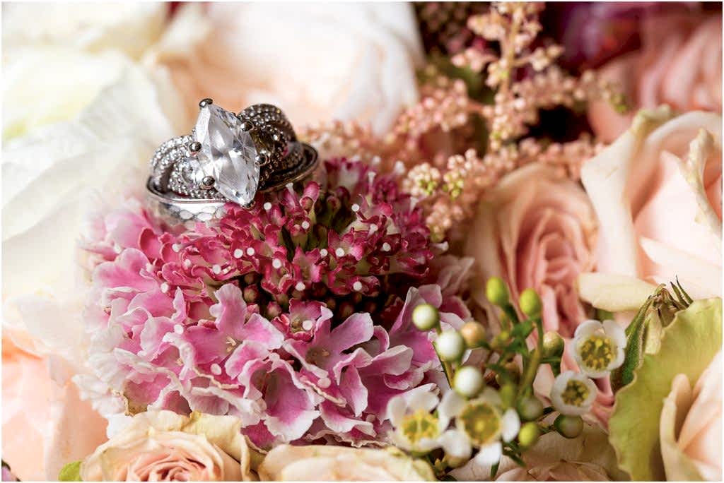 silver oval wedding ring set in pink bouquet flowers captured by Dallas wedding photographers
