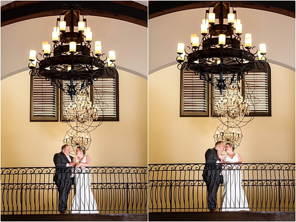 Dallas wedding photographers photograph bride holding grooms face under large chandeliers at luxury Ana Villa wedding venue