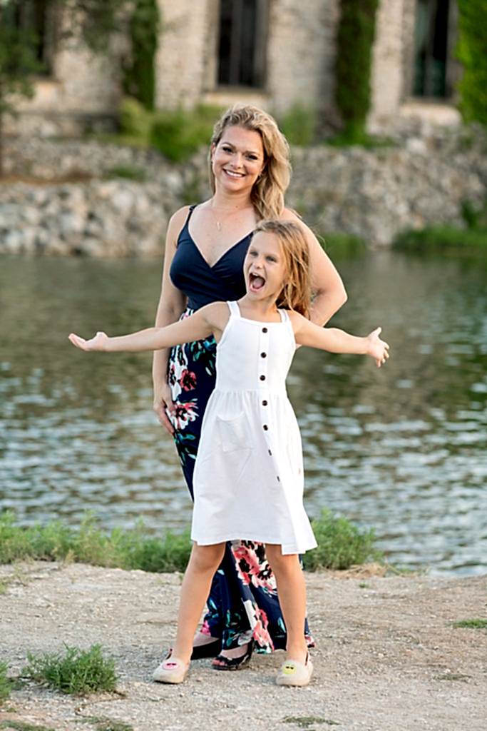 Dallas family photographer captures daughter with arms out in front of mom at Adriatica Village Portrait Location