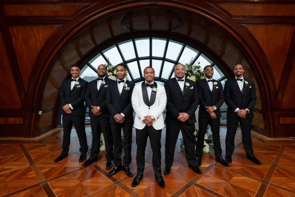 Groom and his groomsmen posing in front of a large half moon window