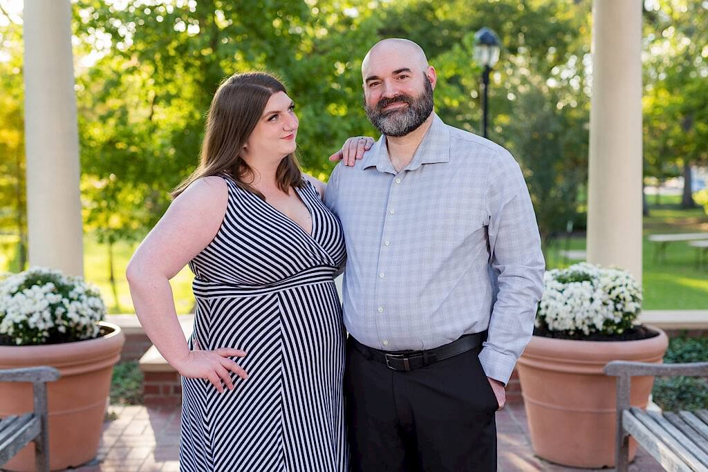 Woman looking sweetly at fiancé while he smiles at the camera on the TWU campus during engagement session