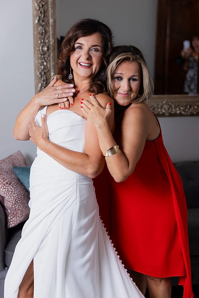 maid of honor wearing red hugging bride in bridal suite at Stoney Ridge Villa