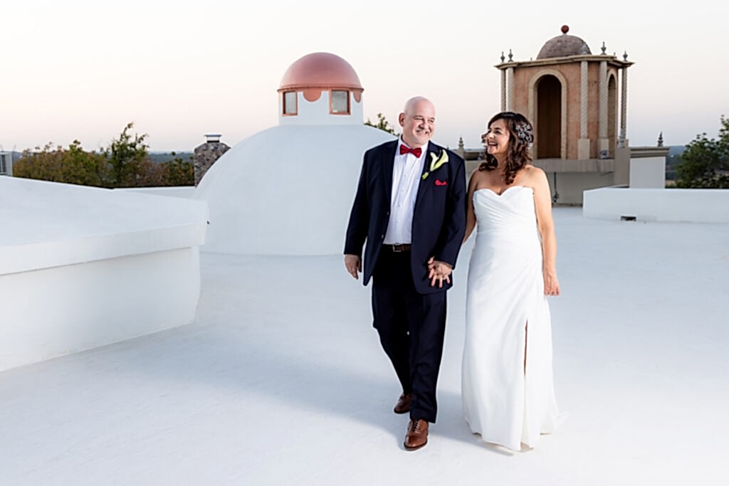 Bride and groom walking hand in hand in wedding attire on rooftop at Stoney Ridge Villa wedding venue in Azle, TX