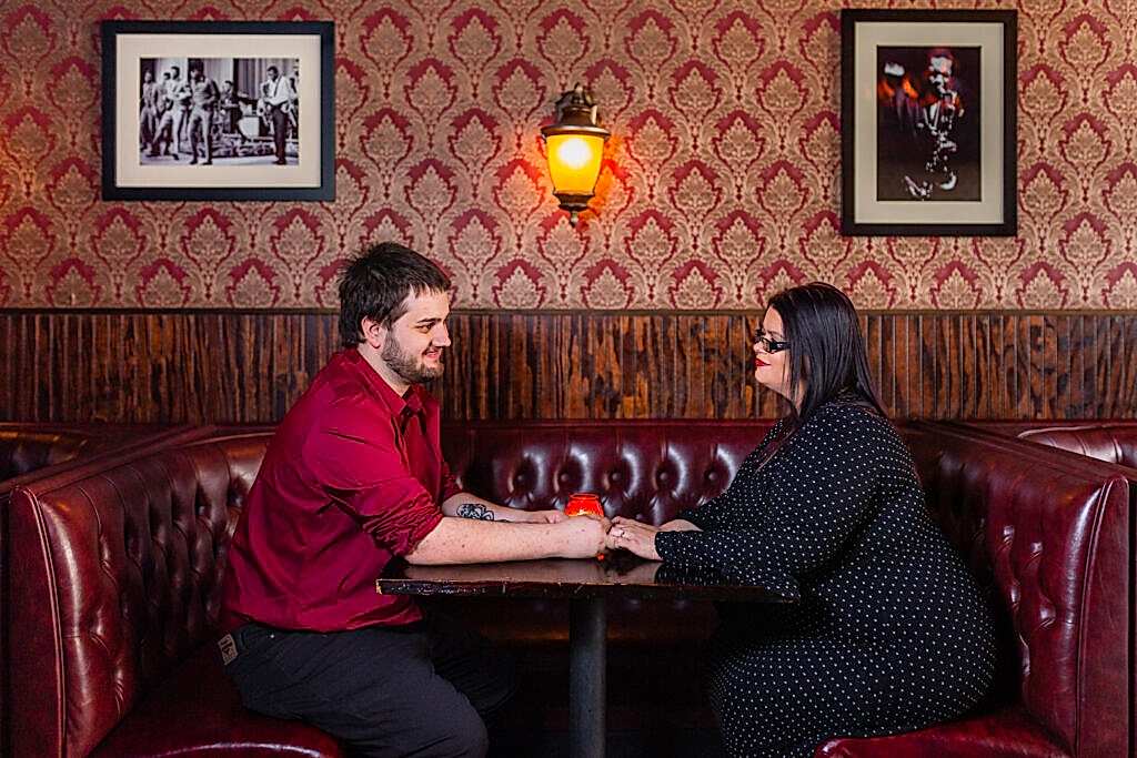 Engaged man and woman holding hands over table in Deep Ellum bar in downtown Texas