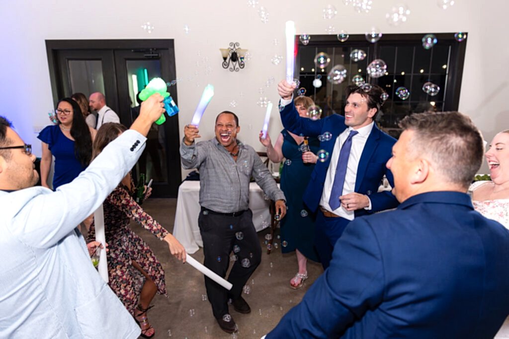 Wedding guests dancing and playing with LED glow sticks and bubble guns