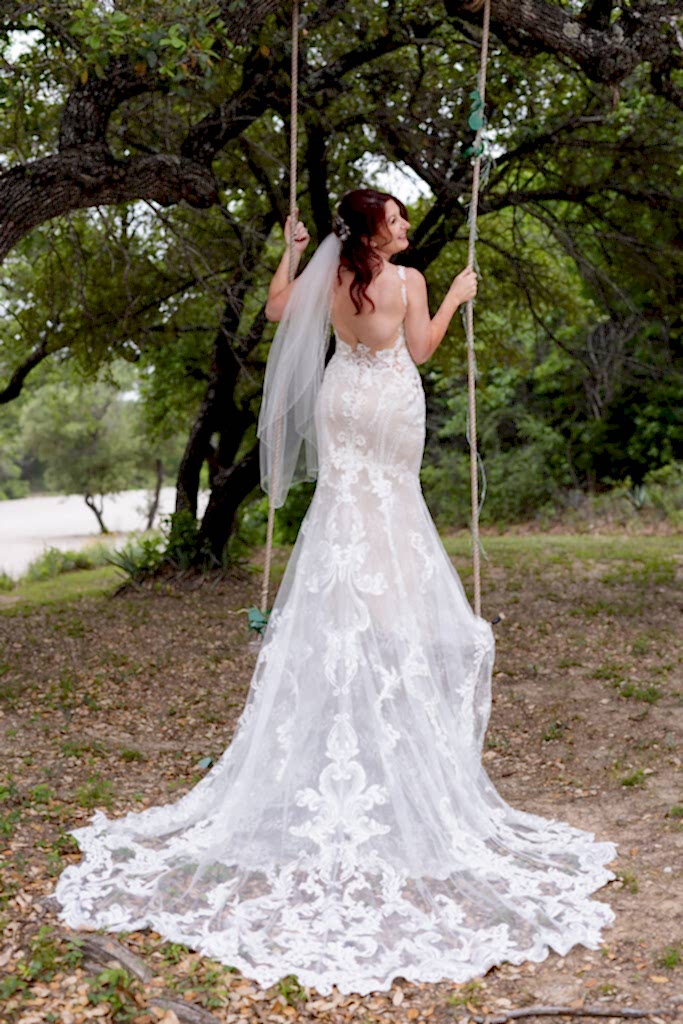 Bride on tree swing with intricate and elegant wedding dress train flowing down