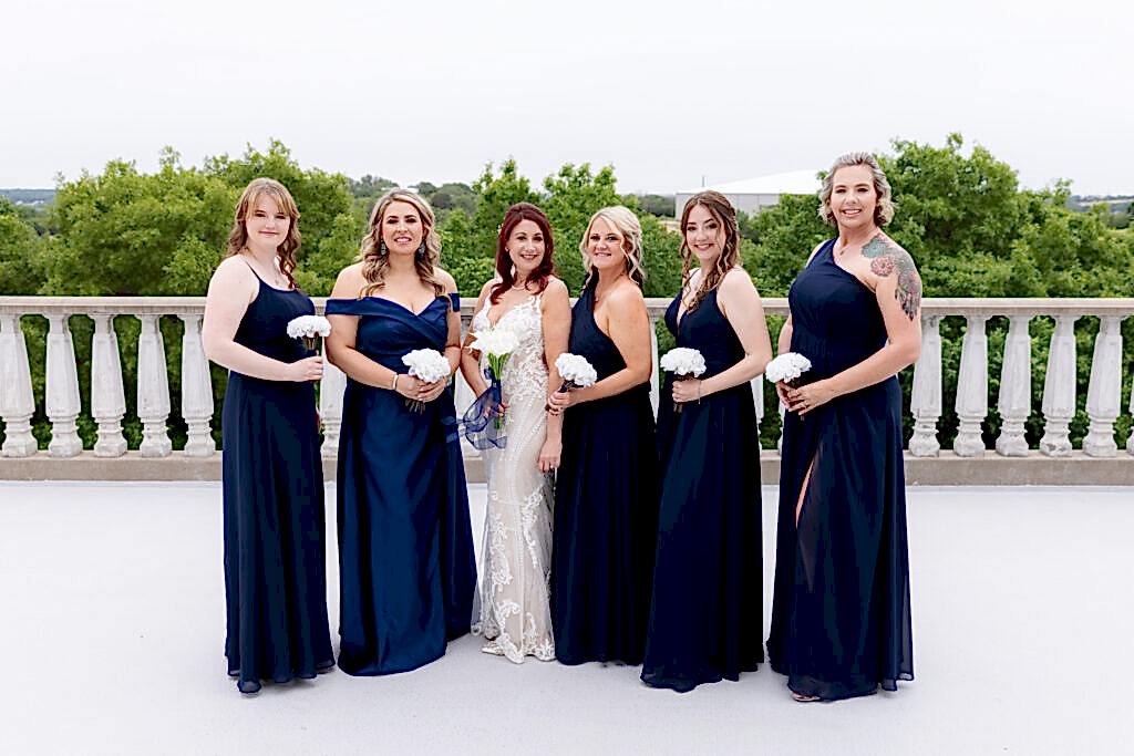 Bride and bridesmaids in blue dresses smiling at camera