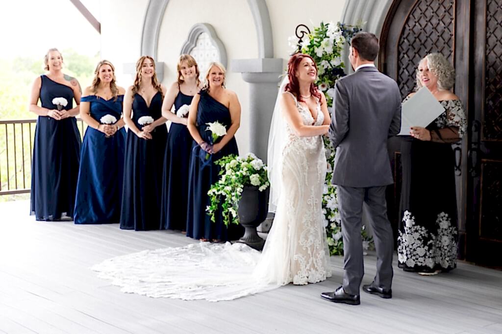 Bride and groom holding hands smiling while officiant and bridesmaids smile
