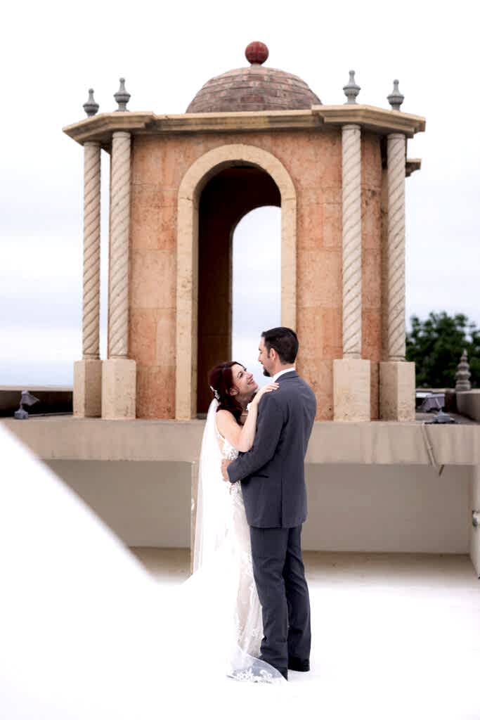Bride and groom dancing on wedding venue rooftop near bell tower
