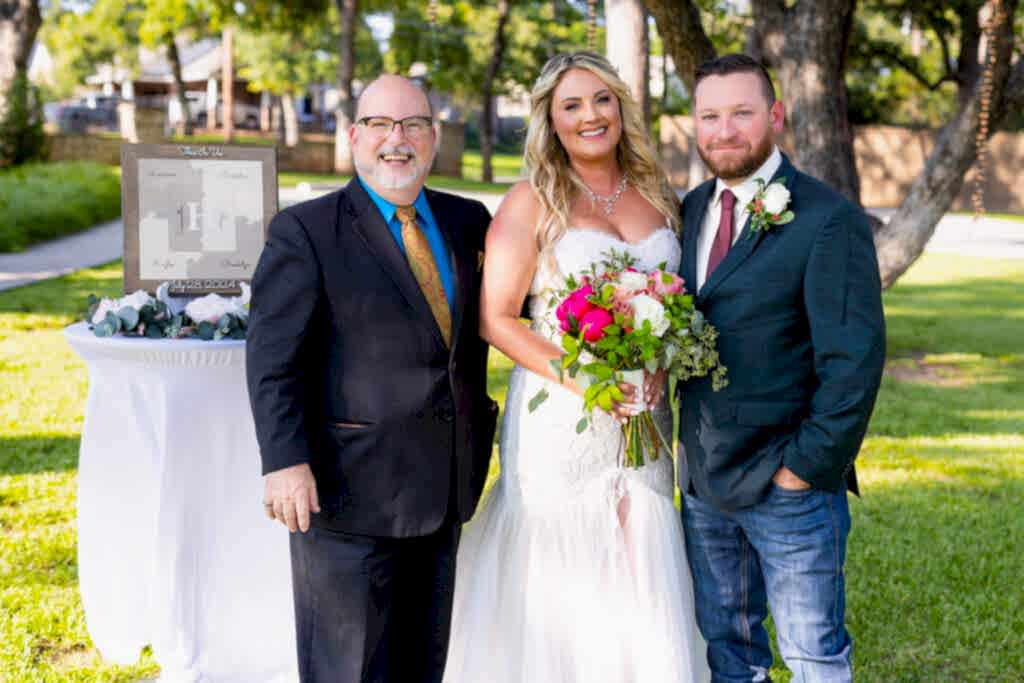 Bride, groom and officiant smiling at the camera after ceremony