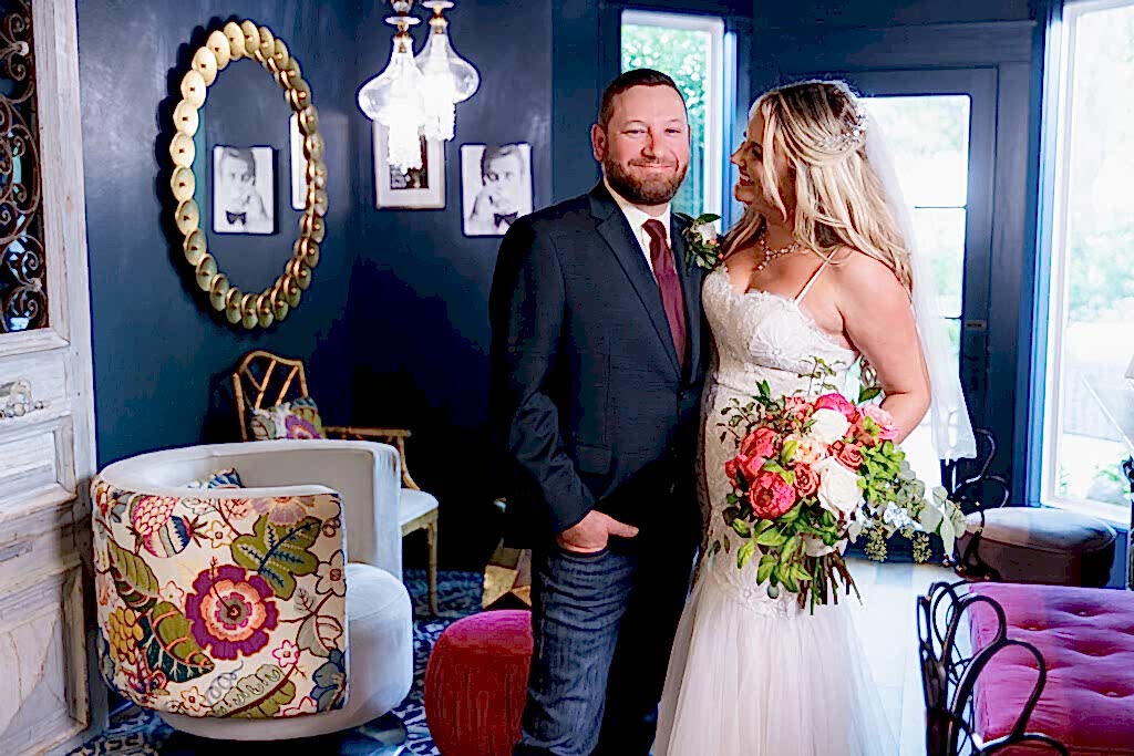 Bride smiles at groom smiling at camera inside blue hotel bar