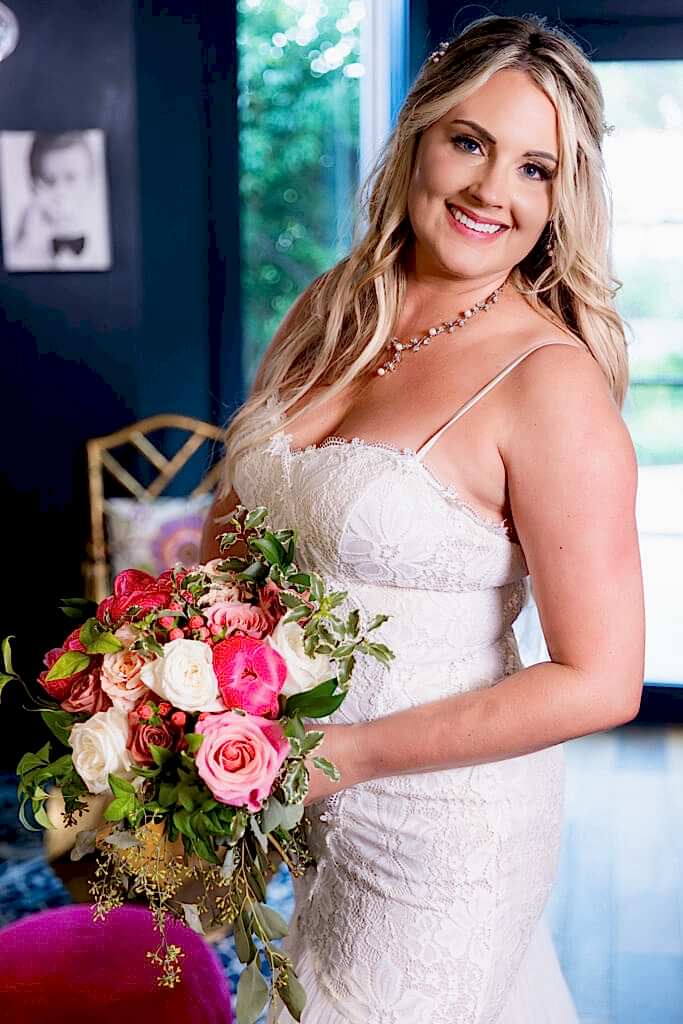 Bride holding pink flower wedding bouquet inside cute and chic blue hotel bar