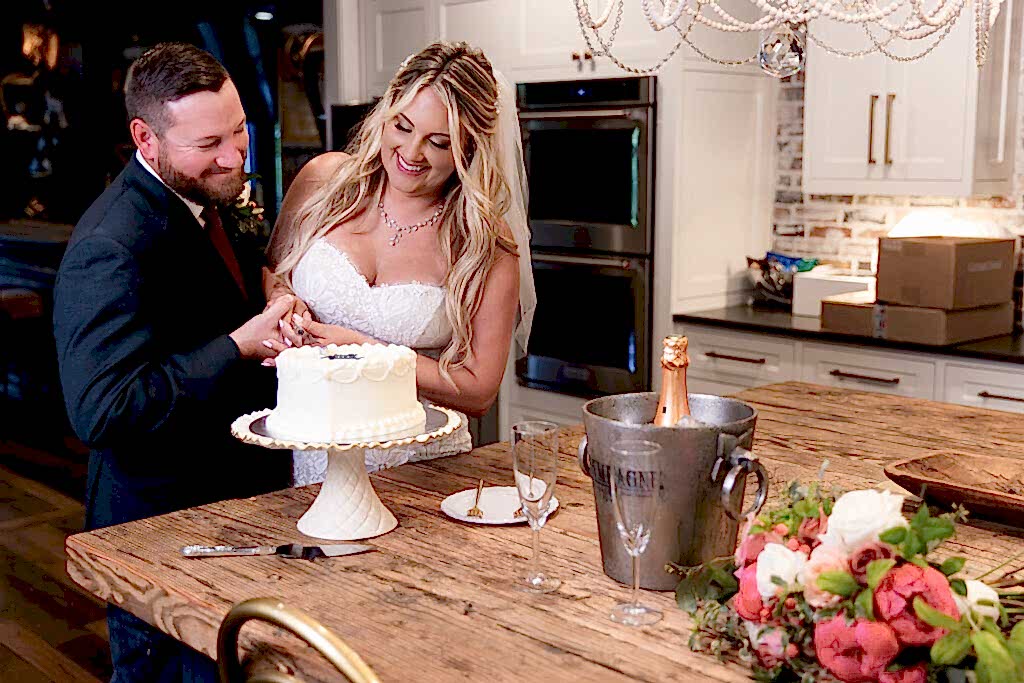 Bride and groom cutting simple heart shaped cake in Hotel Lucy's kitchen