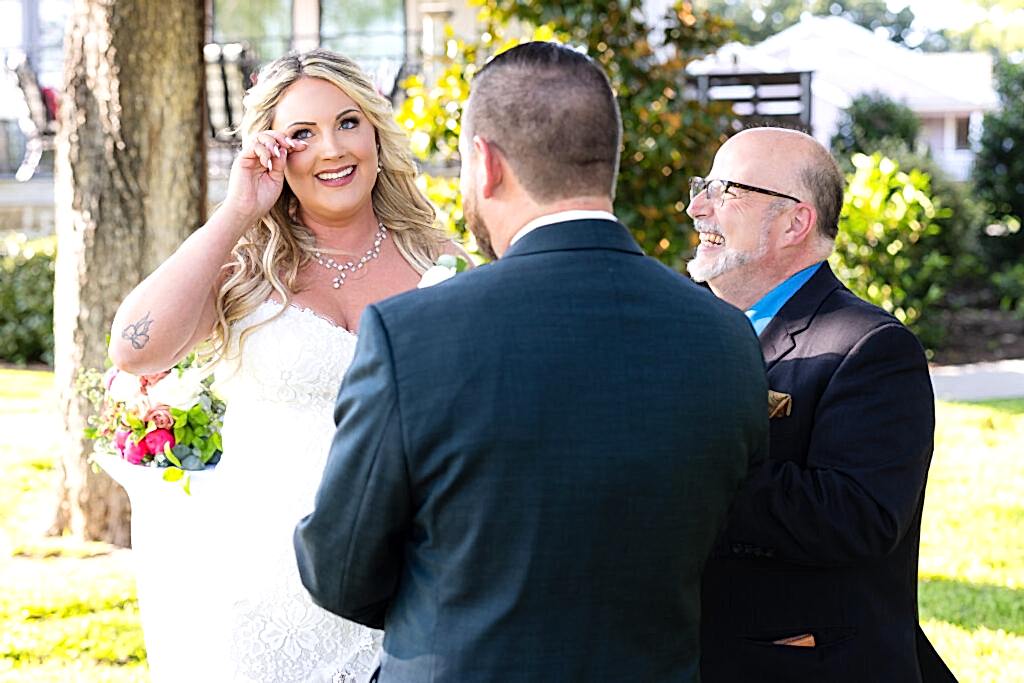 Bride wiping tear while smiling during outdoor intimate elopement ceremony