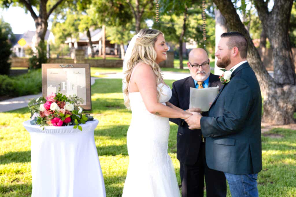 Bride and groom smiling and holding hands during intimate elopement wedding ceremony on lawn at Hotel Lucy