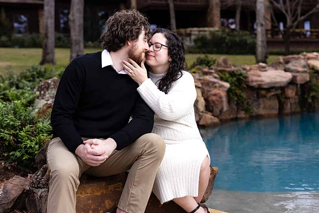 Engaged woman pulling in her fiancé for a kiss by their lakehouse pool