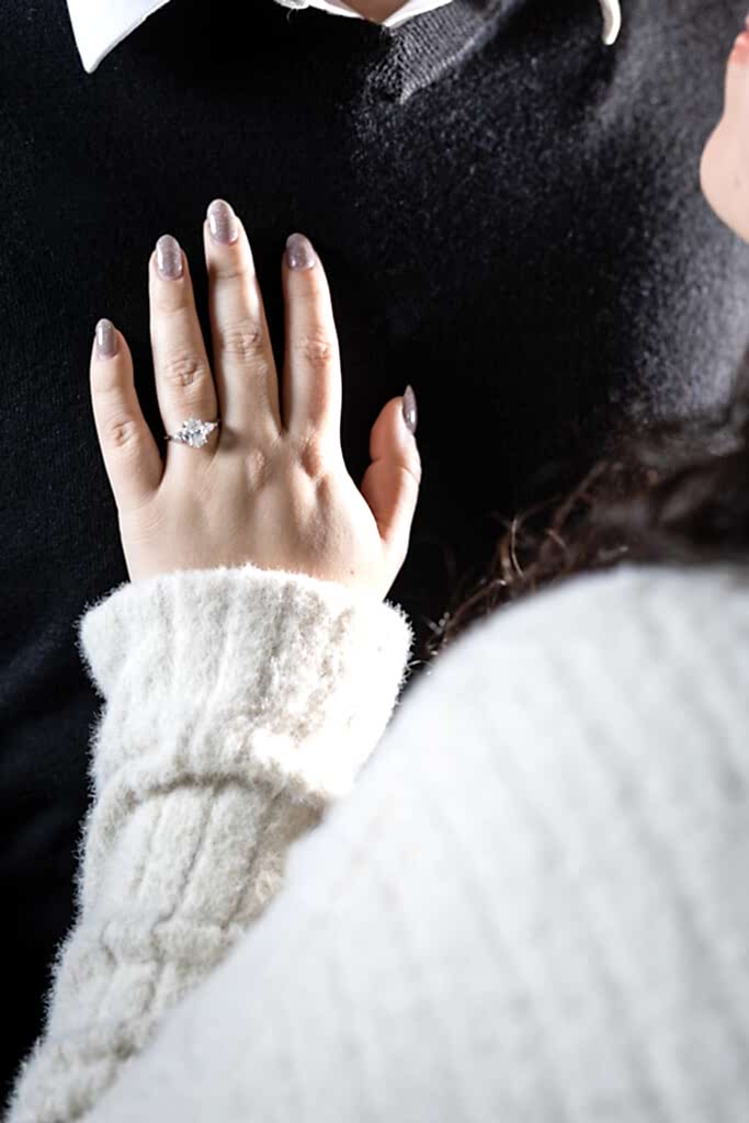 Close up of woman's hand wearing a stunning 3-diamond oval engagement ring