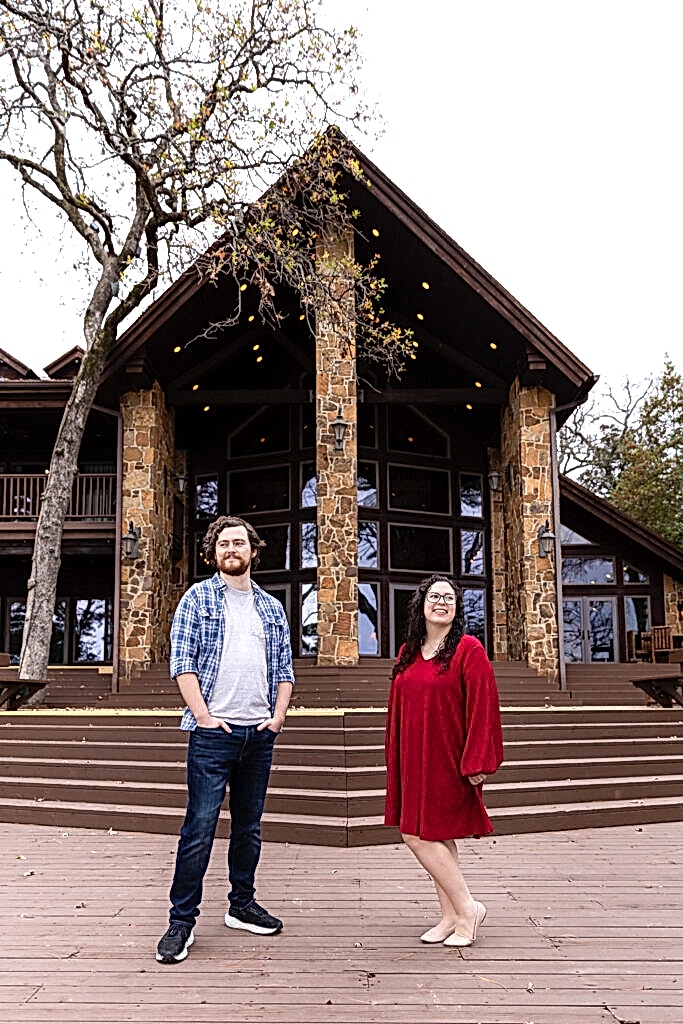 Engaged couple smiling and wearing red, white and blue in front of their gorgeous lakehouse during engagement session in Mabank, TX