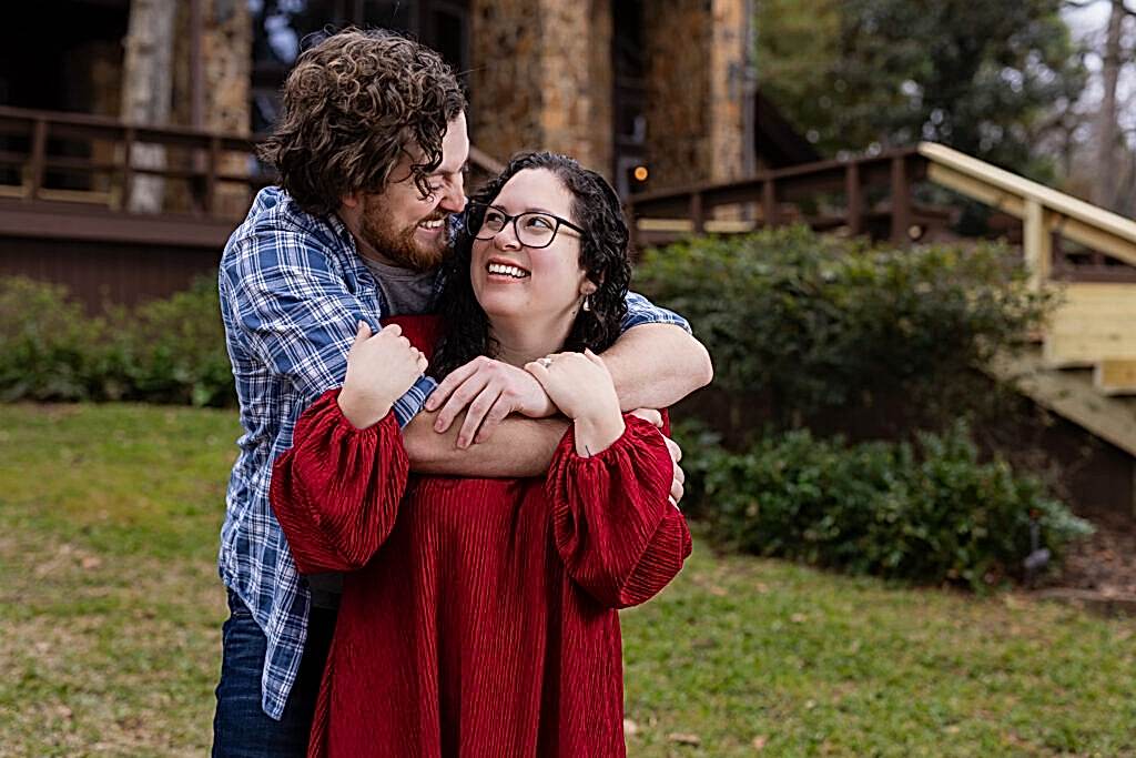 Man hugging fiancée from behind laughing at each other