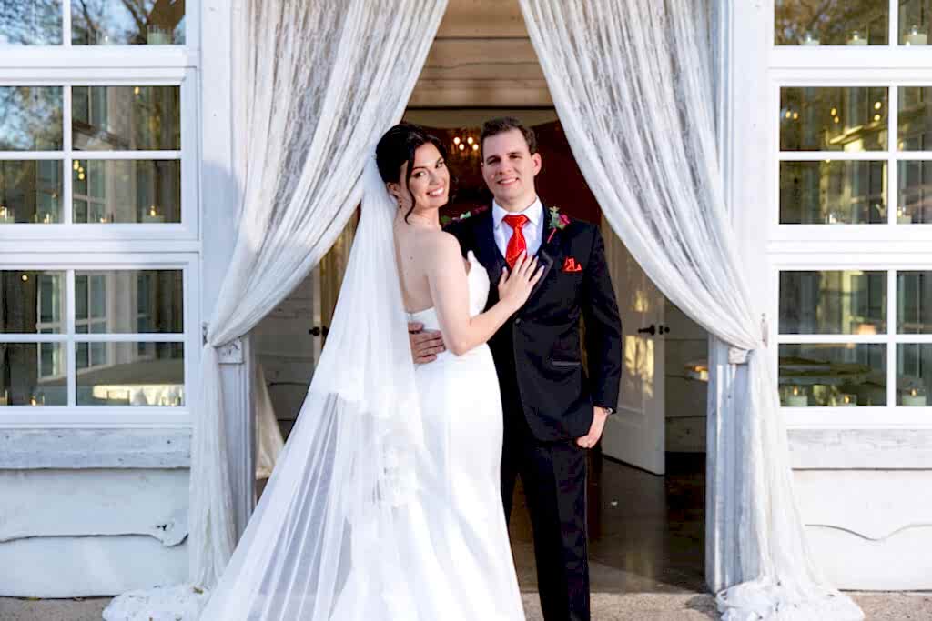 Bride and groom standing in doorway of white Chandler Chapel at Bella Woods venue